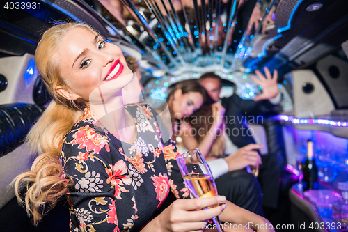 Image of Portrait of smiling young woman holding champagne flute with fri