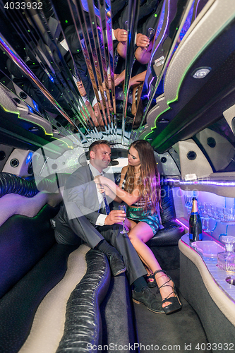 Image of Young woman adjusting tie of boyfriend in limousine