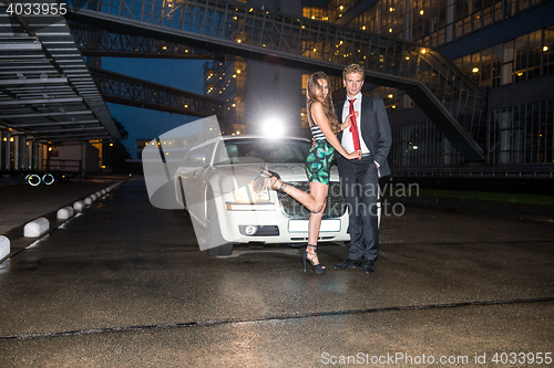 Image of Full length of glamorous young couple standing in front of limou
