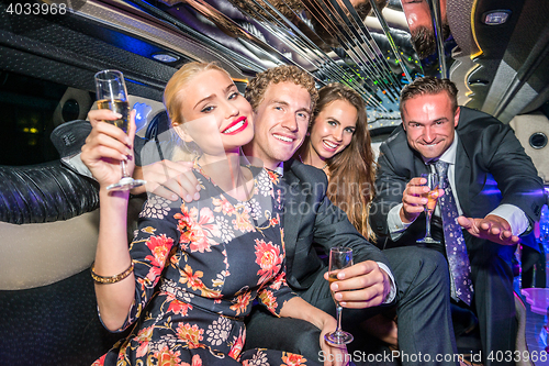 Image of Portrait of young male and female friends with champagne flutes 