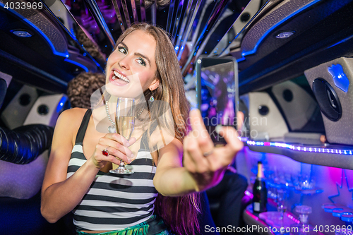 Image of Smiling beautiful woman with champagne flute taking selfie on mo