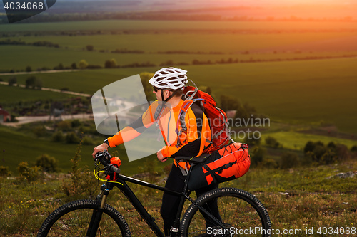Image of Young man cycling on a rural road through green meadow