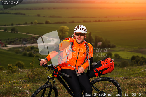 Image of Young man cycling on a rural road through green meadow