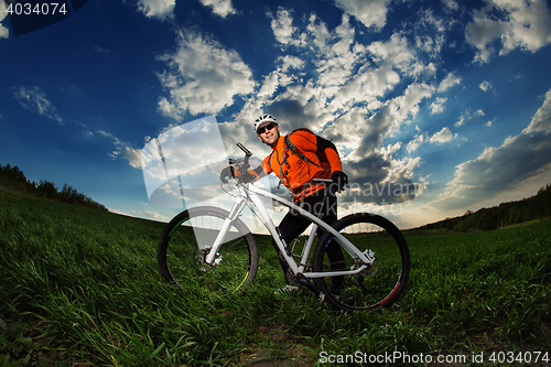 Image of Man Cyclist with bike on sunset