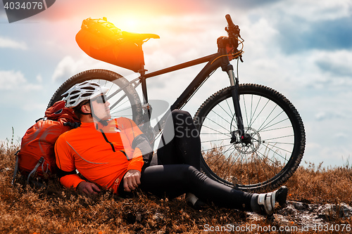 Image of Young man cycling on a rural road through green meadow