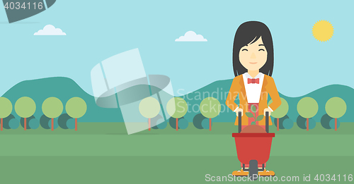 Image of Woman with plant and wheelbarrow.