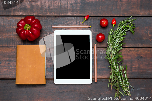 Image of The tablet, notebook, fresh bitter and sweet pepper on wooden table background