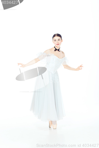 Image of Ballerina in white dress posing on pointe shoes, studio background.