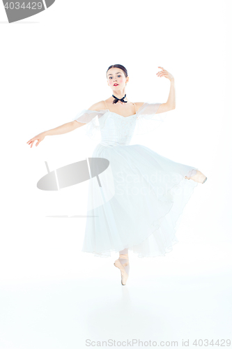 Image of Ballerina in white dress posing on pointe shoes, studio background.