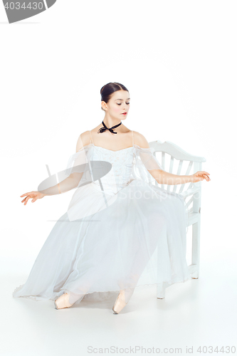 Image of Ballerina in white dress sitting, studio background.