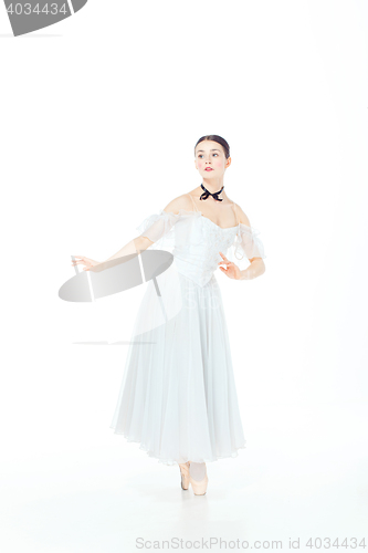 Image of Ballerina in white dress posing on pointe shoes, studio background.