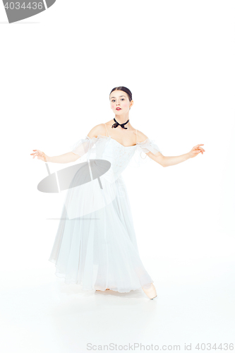 Image of Ballerina in white dress posing on pointe shoes, studio background.