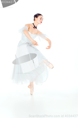 Image of Ballerina in white dress posing on pointe shoes, studio background.