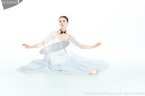 Image of Ballerina in white dress sitting, studio background.