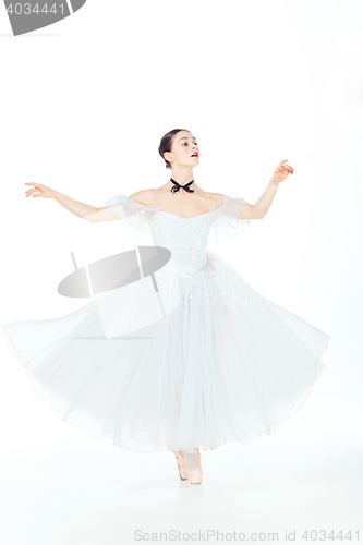 Image of Ballerina in white dress posing on pointe shoes, studio background.