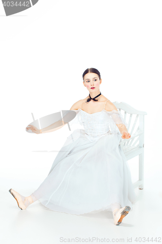 Image of Ballerina in white dress sitting, studio background.