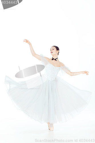 Image of Ballerina in white dress posing on pointe shoes, studio background.