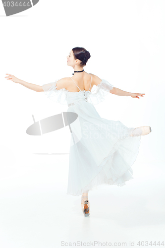 Image of Ballerina in white dress posing on pointe shoes, studio background.