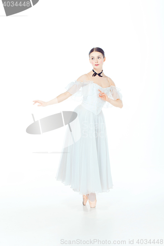 Image of Ballerina in white dress posing on pointe shoes, studio background.