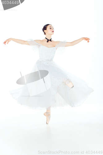 Image of Ballerina in white dress posing on pointe shoes, studio background.