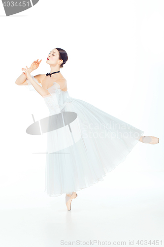 Image of Ballerina in white dress posing on pointe shoes, studio background.