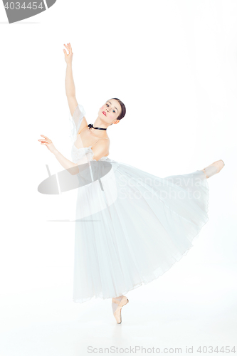 Image of Ballerina in white dress posing on pointe shoes, studio background.