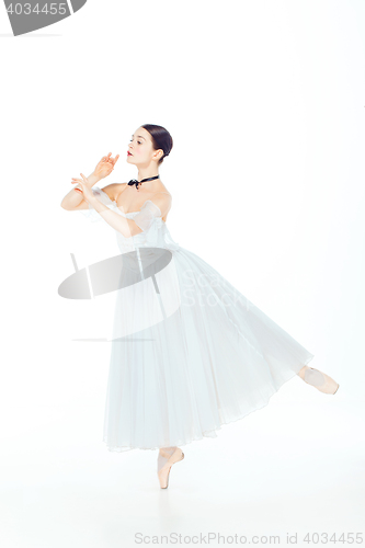 Image of Ballerina in white dress posing on pointe shoes, studio background.