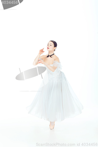 Image of Ballerina in white dress posing on pointe shoes, studio background.