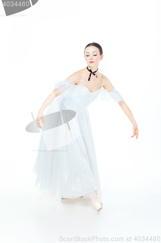 Image of Ballerina in white dress posing on pointe shoes, studio background.