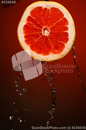 Image of Fresh water drops on grapefruit at red background