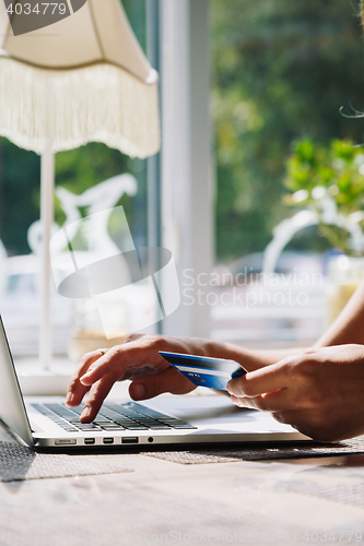 Image of woman using laptop with credit card in hand