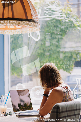 Image of Young short-haired woman using laptop in cafe