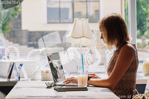 Image of Young short-haired woman using laptop in cafe