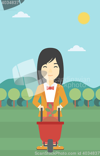 Image of Woman with plant and wheelbarrow.