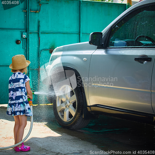 Image of Little girl helps her parents to wash the car