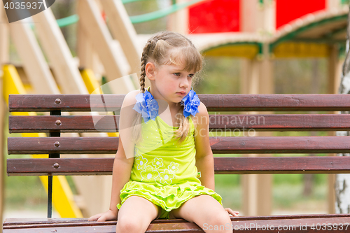 Image of Offended five year old girl sitting on a bench and crying