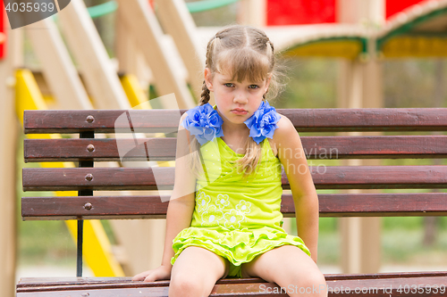 Image of Offended five year old girl sitting on a bench at the playground