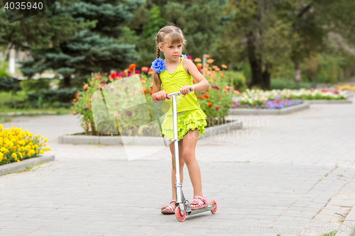 Image of Girl riding a scooter down the avenue