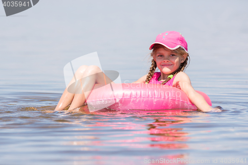 Image of The girl in the cap swim in the river sat on the lap swimming and looked into the frame