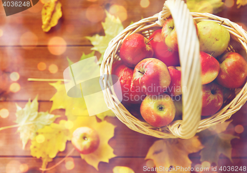 Image of close up of basket with apples on wooden table