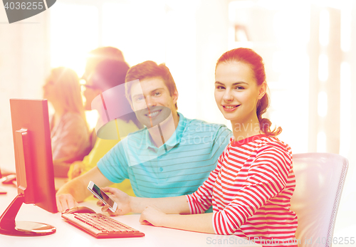 Image of smiling student with smartphone in computer class