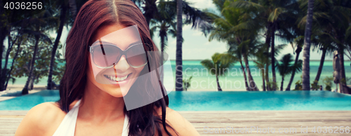 Image of smiling young woman with sunglasses on beach
