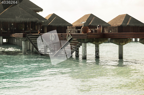 Image of bungalow huts in sea water on exotic resort beach