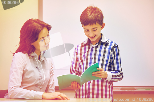 Image of school boy with notebook and teacher in classroom