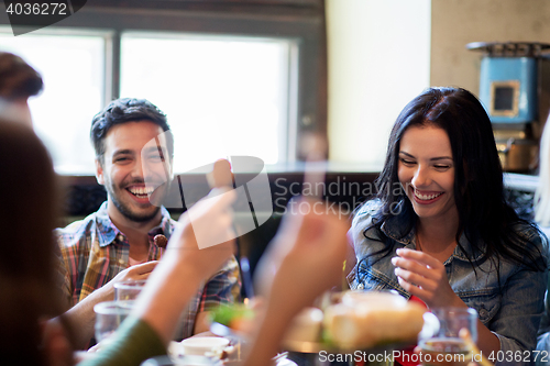 Image of happy friends with beer eating at bar or pub
