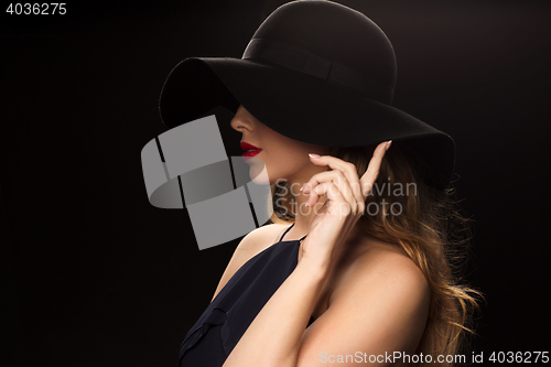 Image of beautiful woman in black hat over dark background