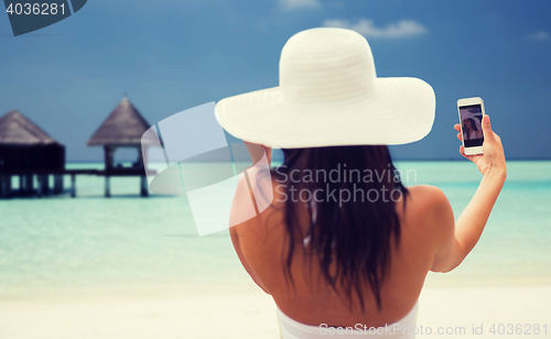 Image of smiling young woman taking selfie with smartphone