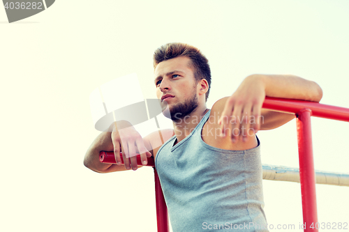 Image of young man exercising on parallel bars outdoors