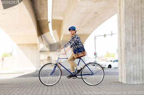 Image of young hipster man with bag riding fixed gear bike