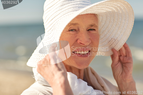 Image of happy senior woman in sun hat on summer beach